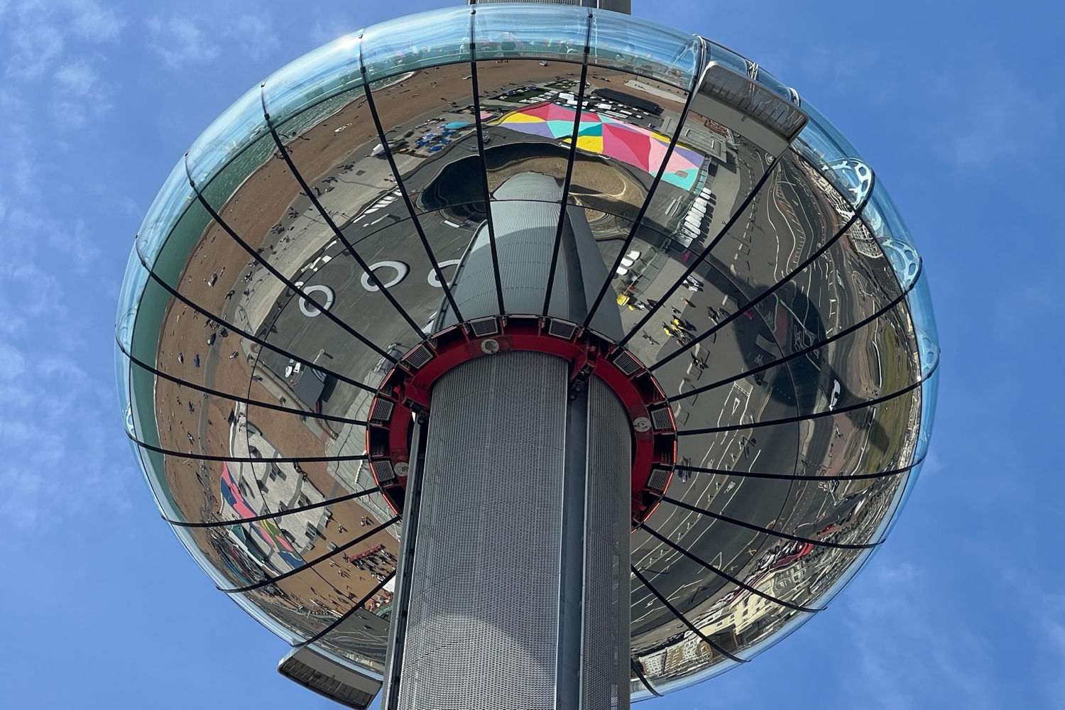 Looking up at the Brighton i360 viewing pod reflecting the seafront and colourful pavement